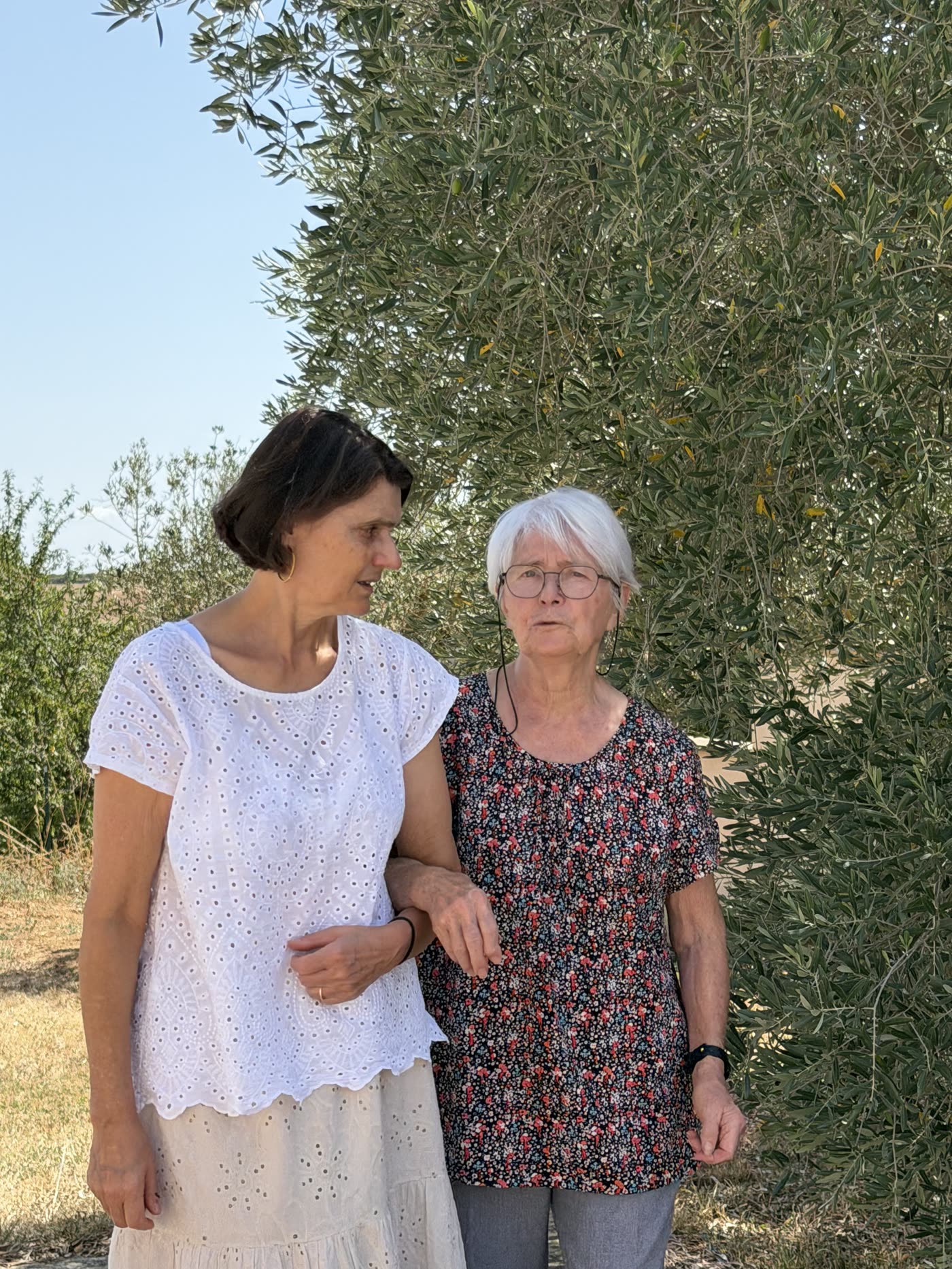 Une accompagnatrice et une personne âgée se promenant bras dessus bras dessous en automne
